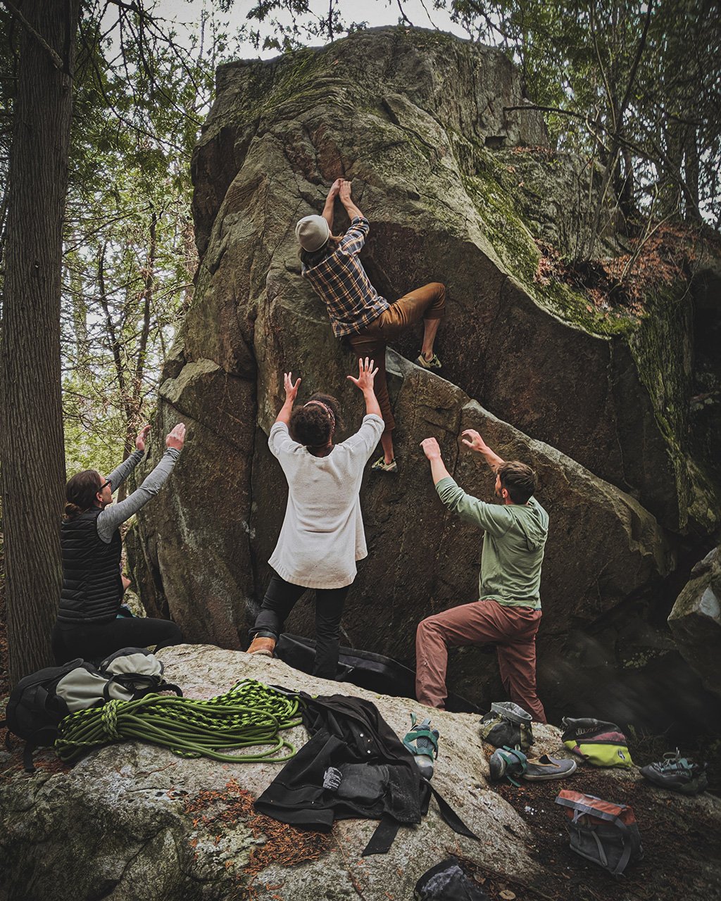 Group of people helping each other climb up a rock